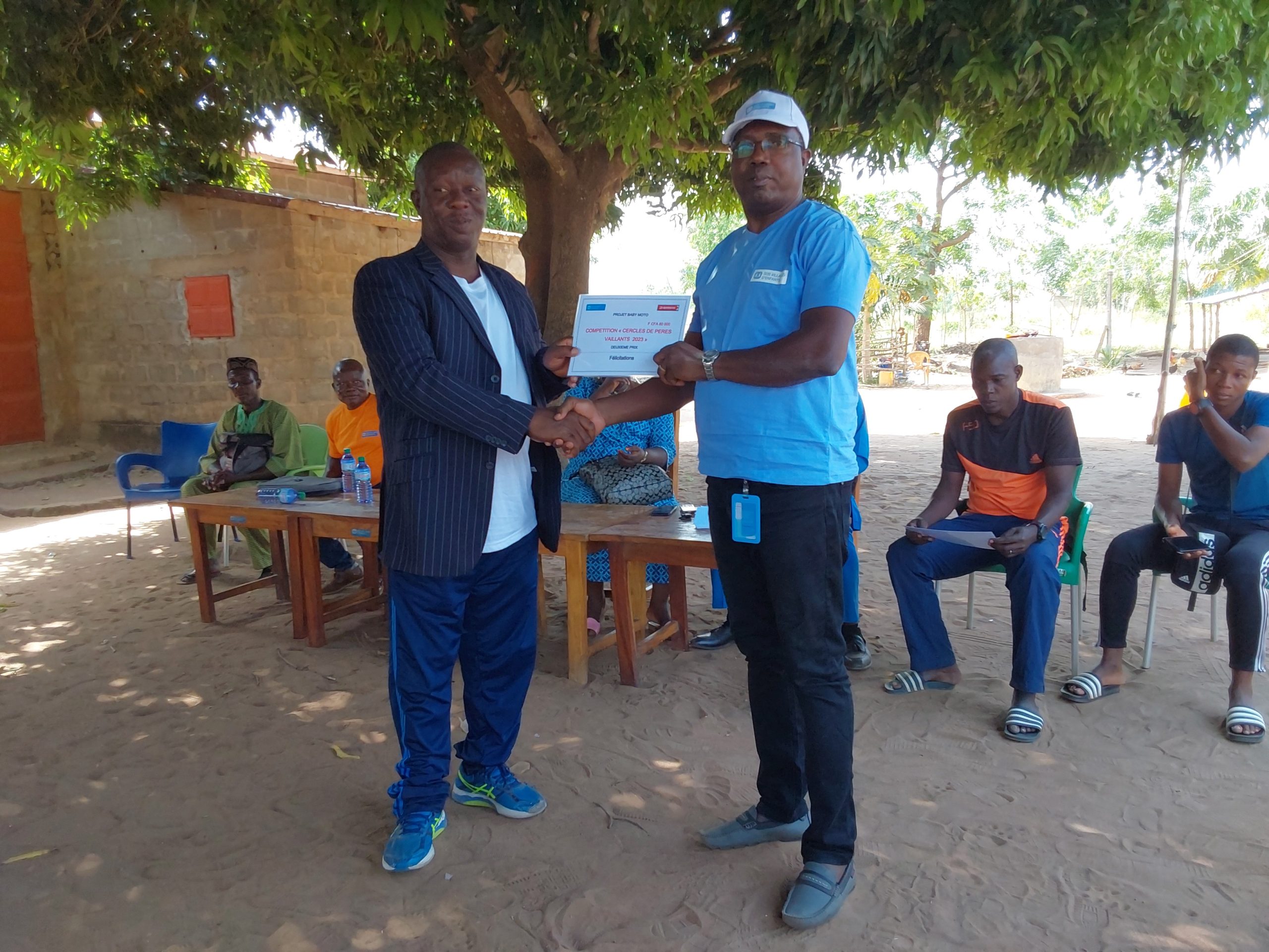 Le manager de SOS Villages dEnfants Atakpame Toeppen Komlan en chapeau remettant le prix aux representant de Glei scaled