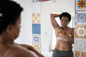 Une femme devant un miroir pour inspecter ses seins