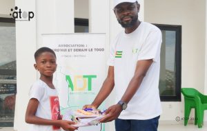 Agoè-Nyivé : Des kits scolaires aux élèves orphelins et nécessiteux 2 70 Le president de lassociation remettant le kit scolaire a un eleve